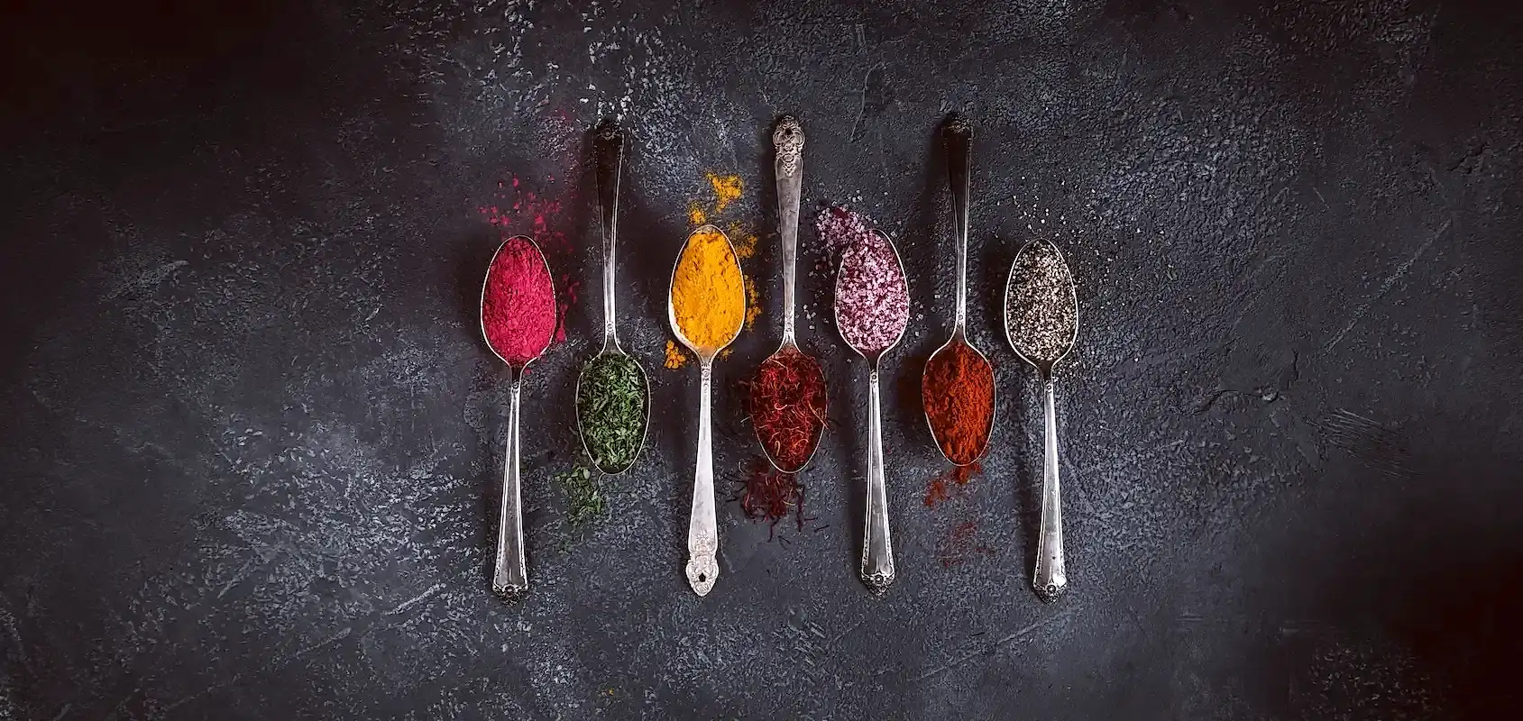 Spoons with spices on a grey background