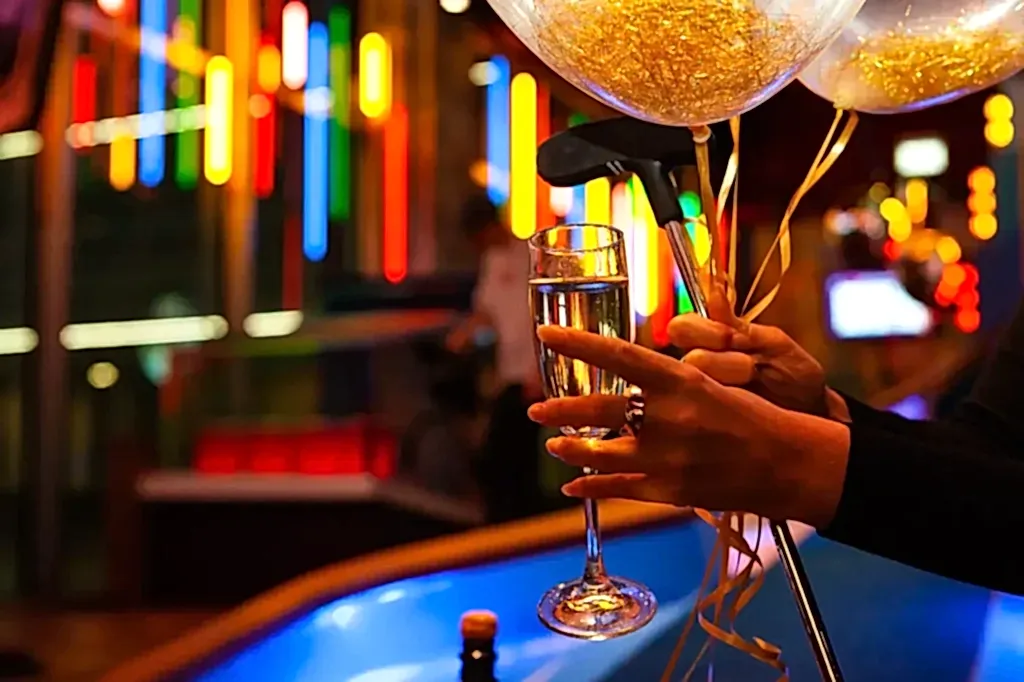 someone holding a glass of bubbly, balloons and a putt