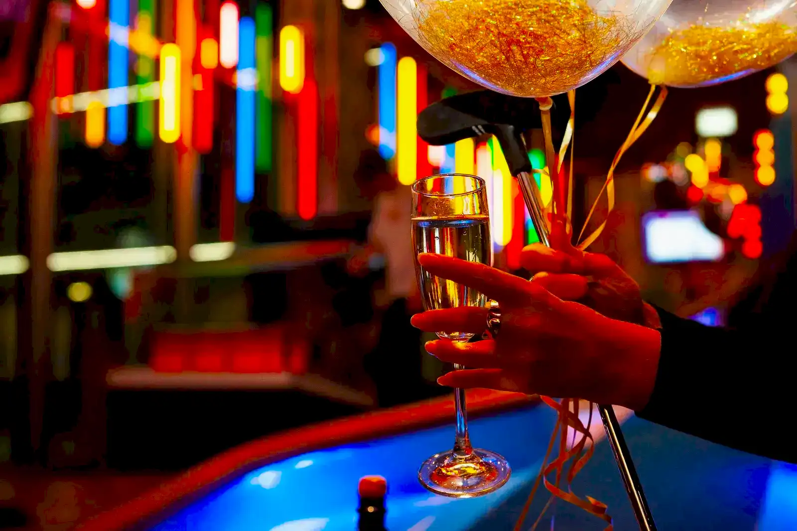 someone holding a glass of bubbly, balloons and a putt