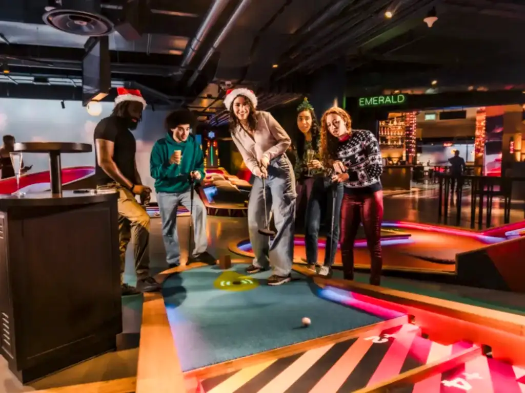 Friends mini golfing at Puttshack in festive Christmas clothing