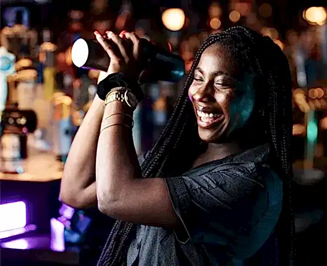 A women smiling and making a mixed drink