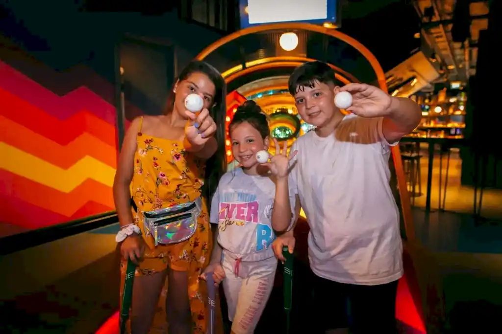 Kids holding up a golf ball at Puttshack