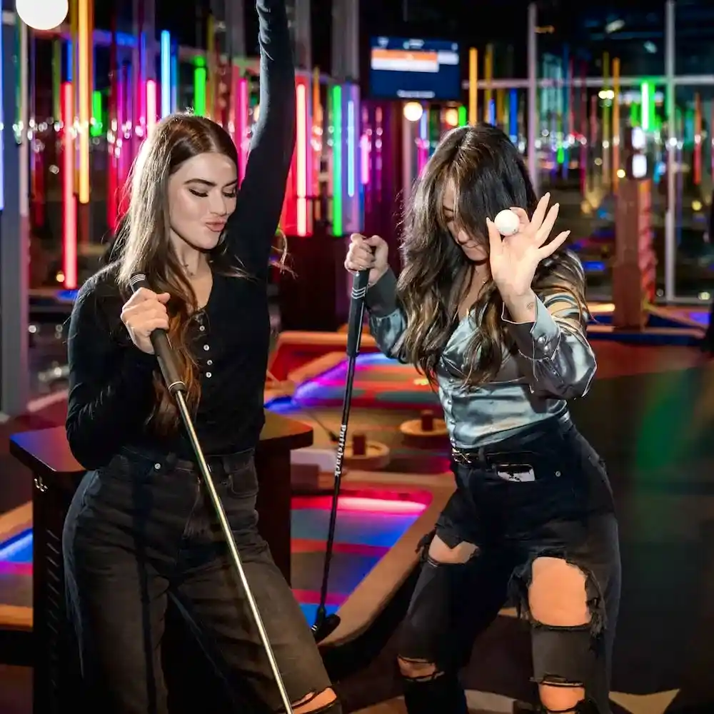 two girls celebrating holding putts and a golf ball