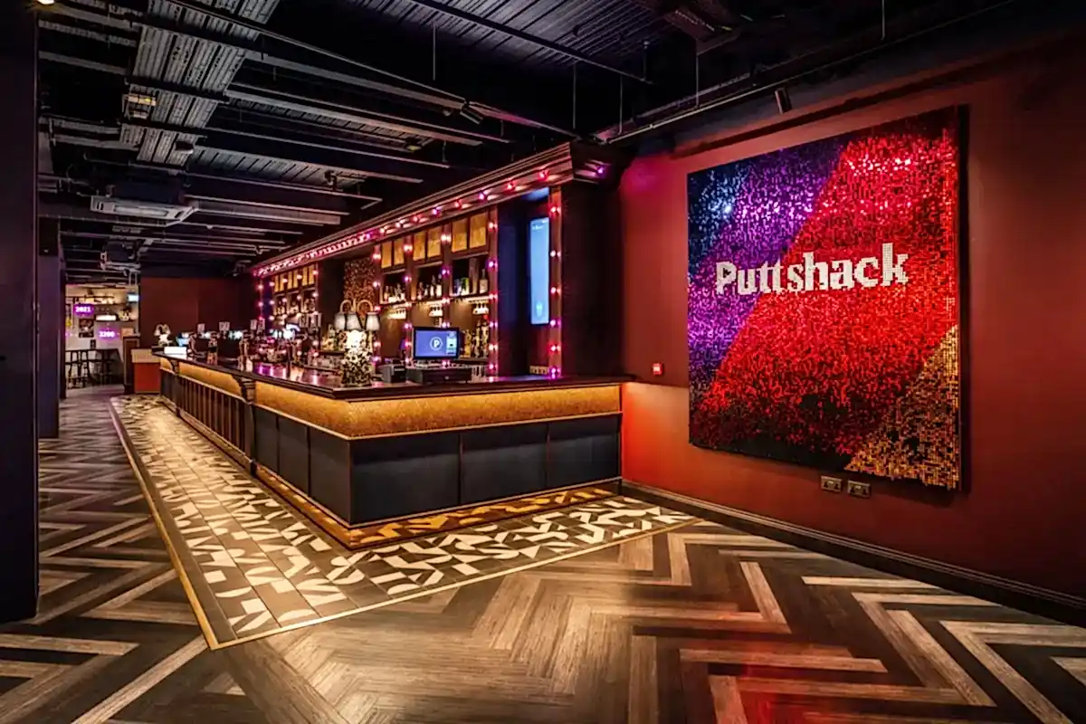 Puttshack Bar with a "Puttshack" blue, purple red, and gold artwork on display