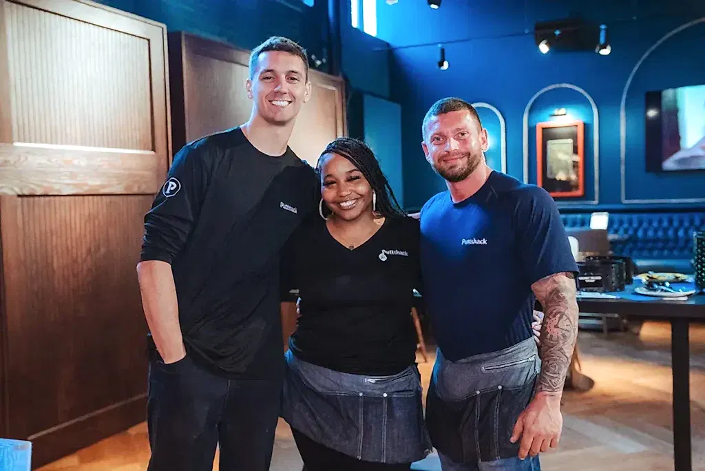 Two male and one female Puttshack employees smiling together