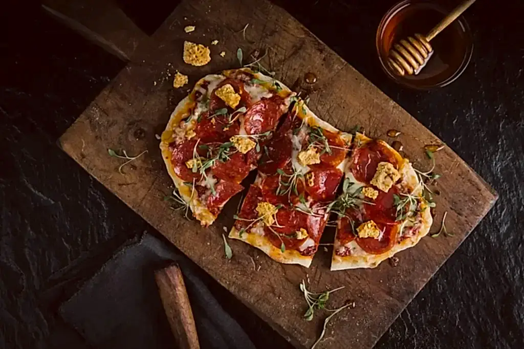 A meat flatbread with a honey ladle