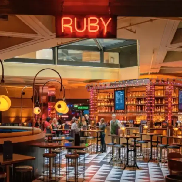 inside a puttshack dining area with a neon RUBY sign